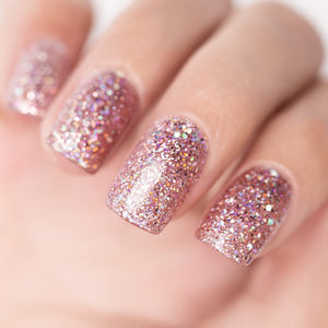 Rose gold glitter manicure with iridescent holographic pink purple silver sparkles on nails close-up