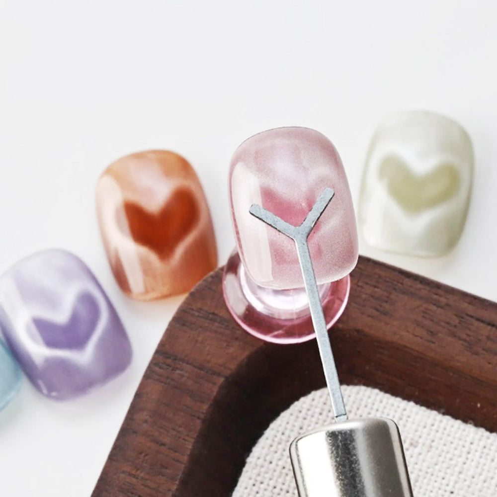 Y-shaped heart magnet tool creating heart patterns on cat eye gel polish pink orange purple blue swatches
